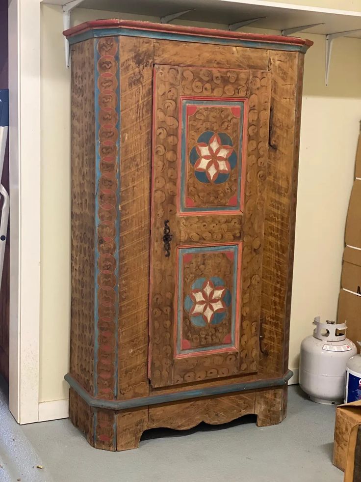 an old wooden cabinet with decorative designs on it's doors and shelves in a storage room