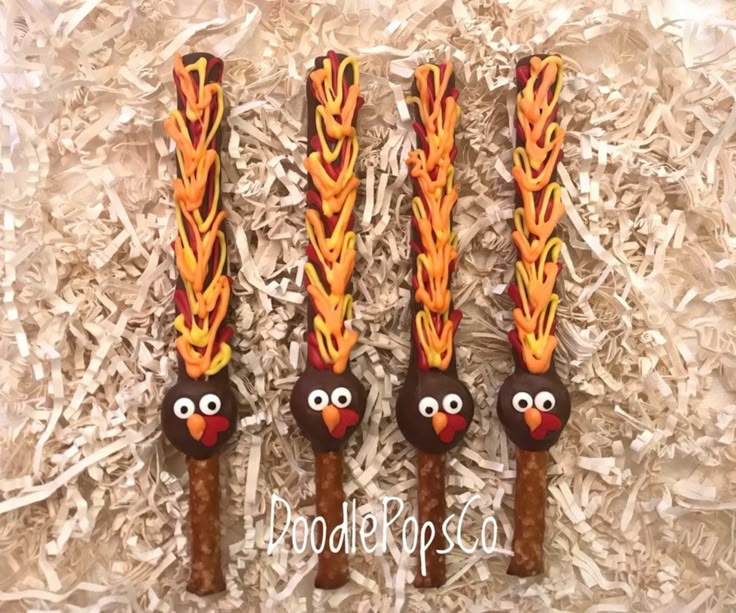 three decorated wooden spoons in the shape of angry birds with orange and yellow feathers