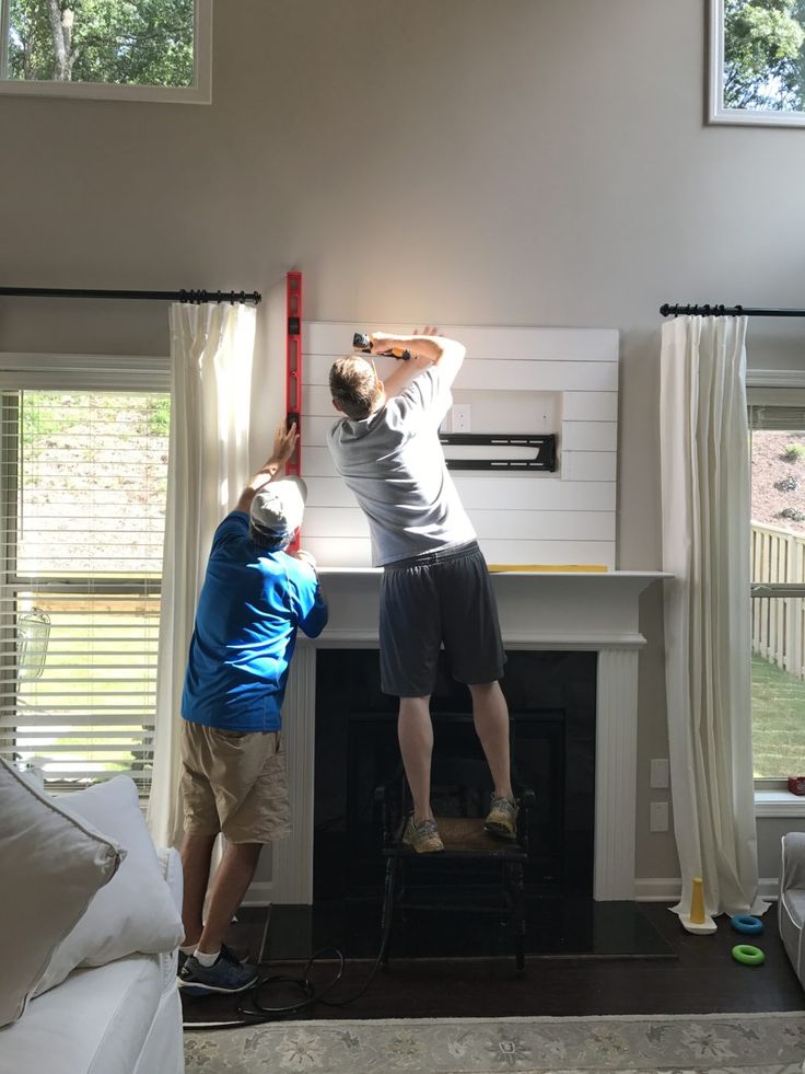 two men working on a fireplace in a living room