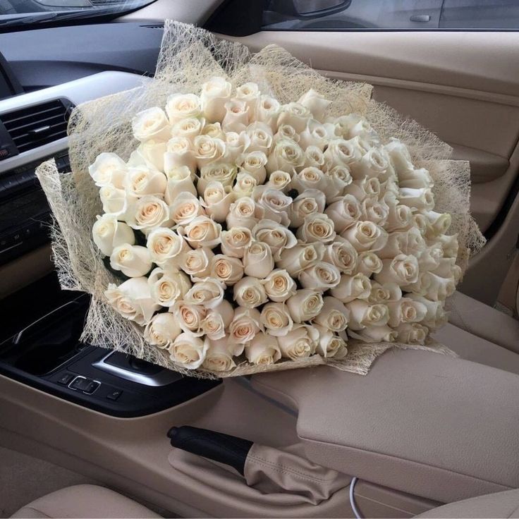 a bouquet of white roses sitting on the dashboard of a car