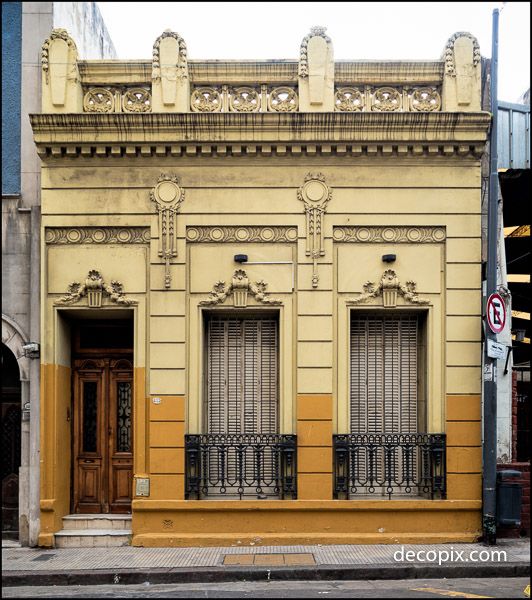 an old yellow building with wrought iron doors and window grills on the side of it