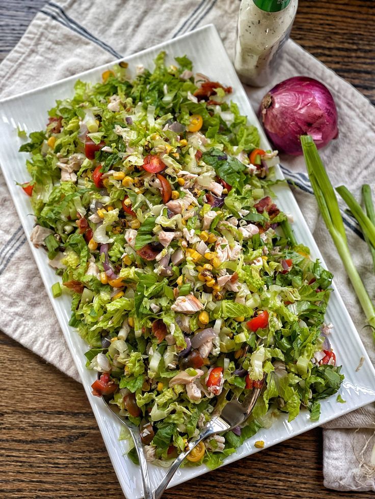 a white plate topped with a salad next to two green onions