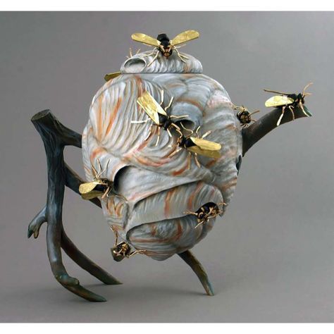 a sculpture of a teapot with bees on it's back legs