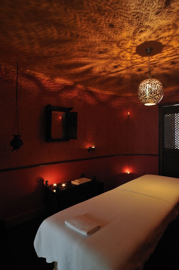 a dimly lit massage room with candles on the walls and a bed in the middle