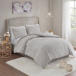 a bed with white comforter and pillows in a room