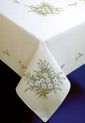 a white table cloth with blue and yellow flowers on it, sitting on a black surface