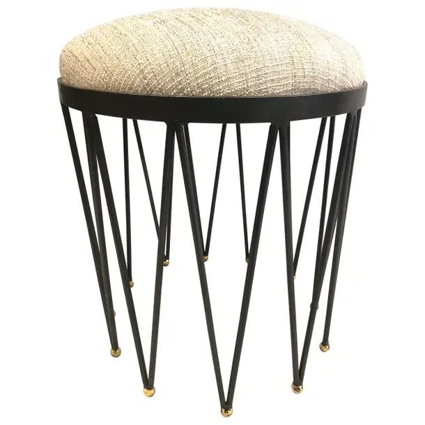 a small stool with metal legs and a beige seat cushion on it's back