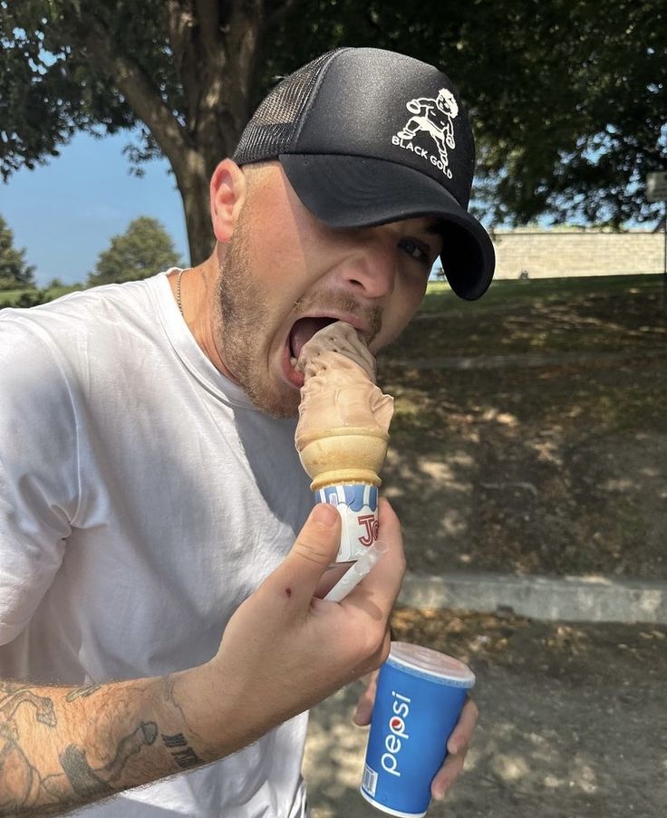 a man eating an ice cream cone with his mouth open and holding a cup in one hand