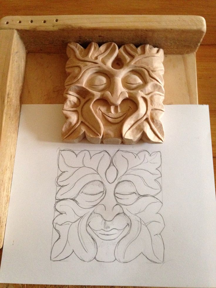 a wooden block with a carved face on it next to a piece of paper that has been cut out