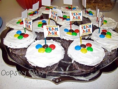 cupcakes decorated with white frosting and colorful candies on a cake platter