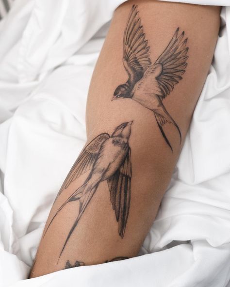 a bird tattoo on the leg of a person laying in bed with white linens