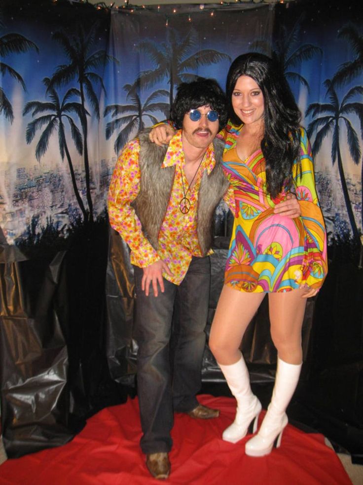 a man and woman posing for a photo in front of a backdrop with palm trees