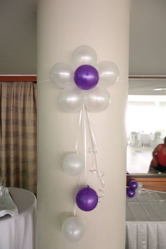 some balloons are hanging on a pillar in front of a white table cloth and curtains