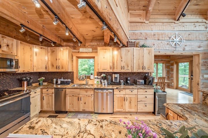 a large kitchen with wooden cabinets and granite counter tops in a log cabin style home