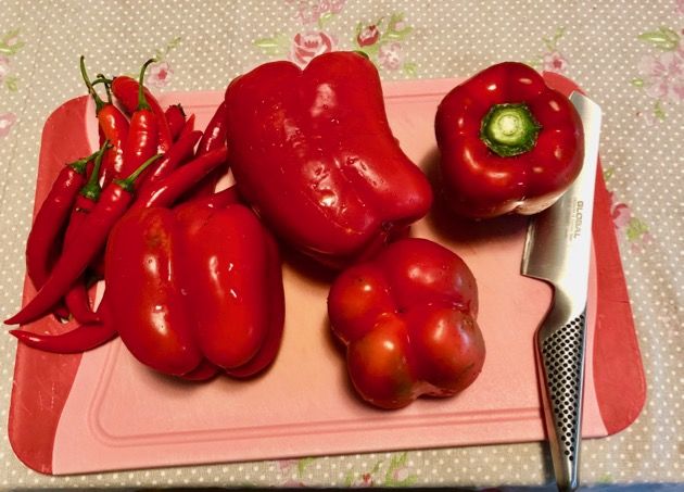 some red peppers are on a pink cutting board