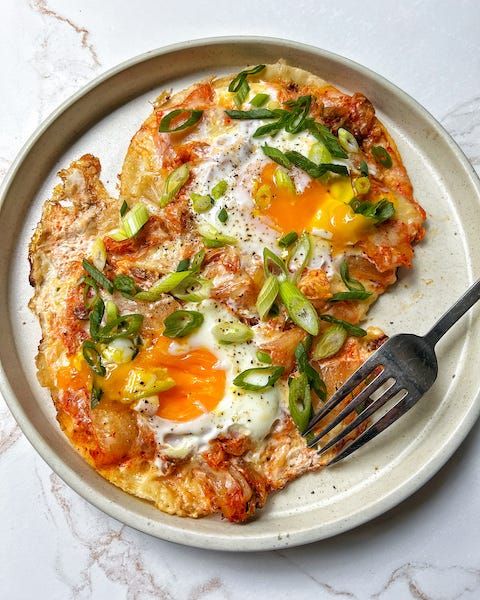 an egg and vegetable pizza on a plate with a fork