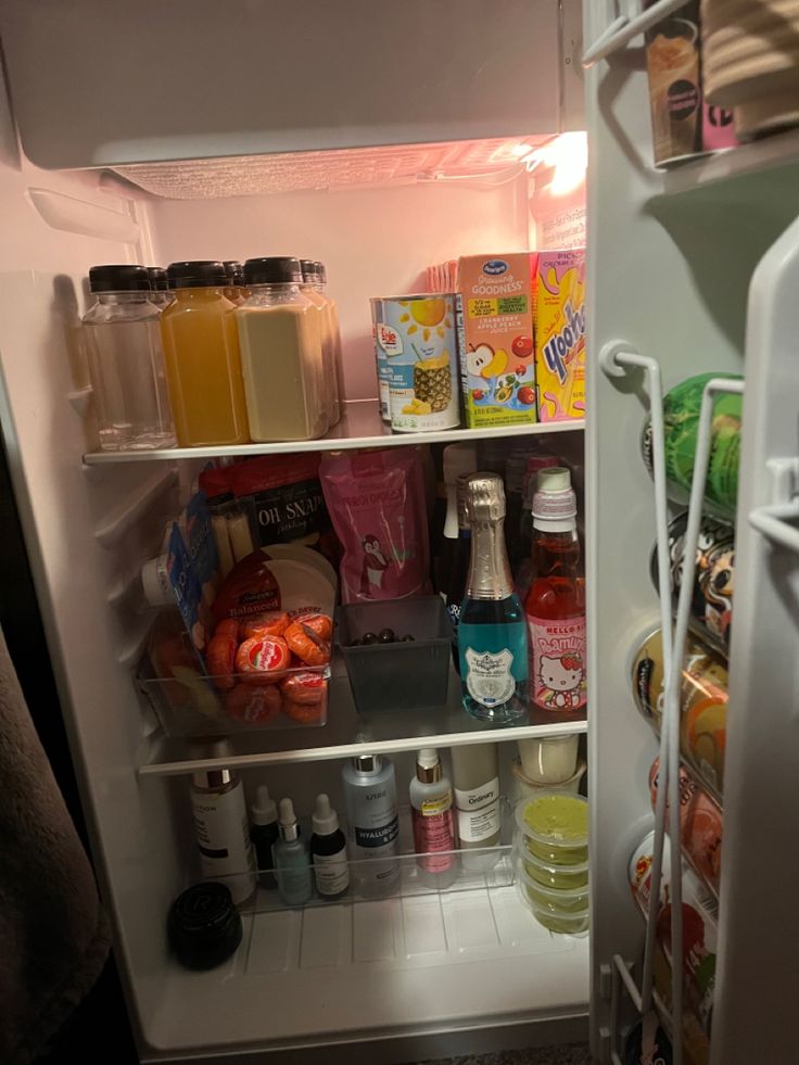 Open mini fridge stopped with skin care drinks and mini wine bottles. College Mini Fridge Food, Min Fridge In Bedroom, Mini Fridge Essentials, Mini Refrigerator Aesthetic, Meal Prep Mini Fridge, College Fridge Organization, Mini Fridge Bedroom Ideas, Rooms With Mini Fridge, Decorated Mini Fridge