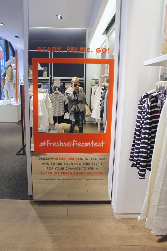 a woman is taking a selfie in a clothing store's display window with her cell phone