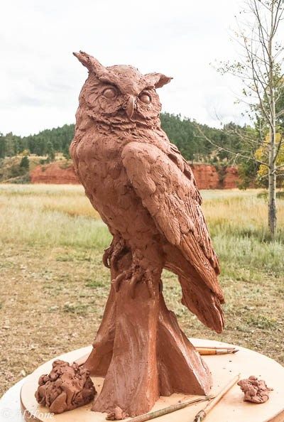 an owl statue sitting on top of a piece of wood