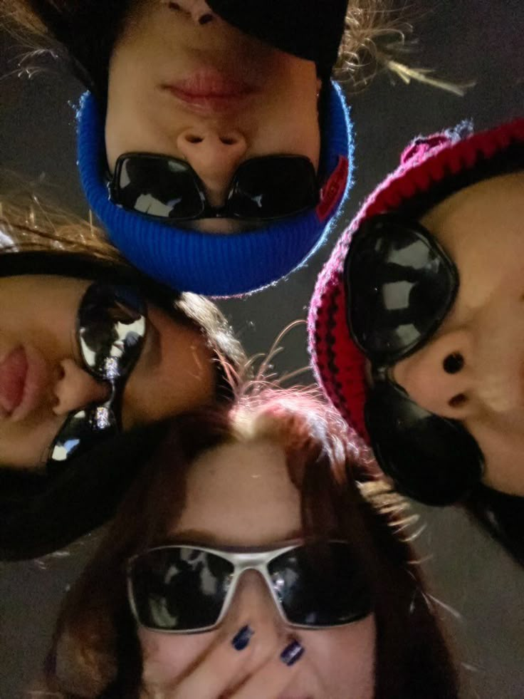 four people wearing sunglasses and hats with their faces together