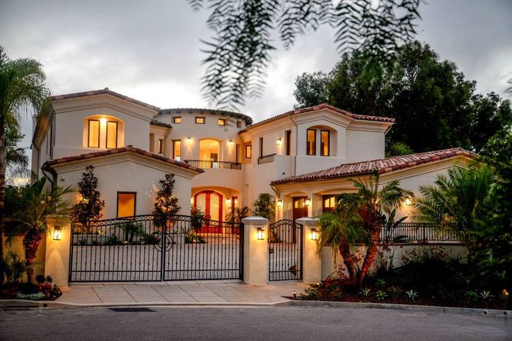 a large white house with lots of windows on it's sides and palm trees in the front yard