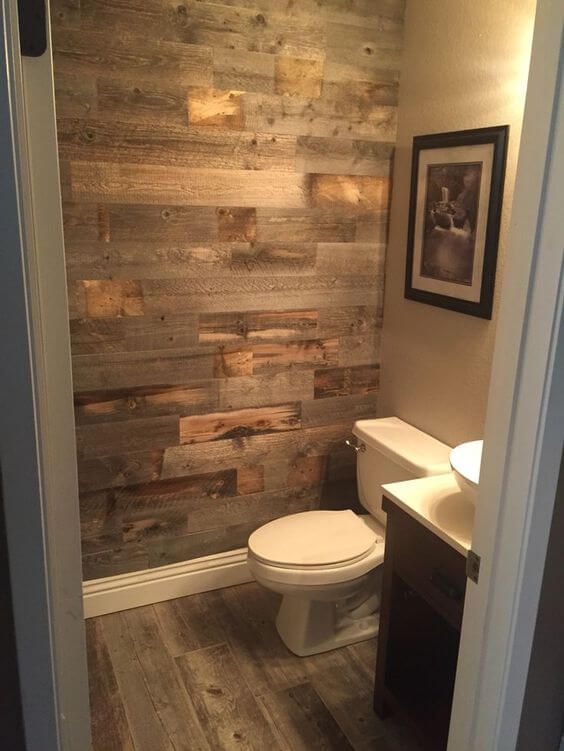 a bathroom with wood planks on the wall and a white toilet in it's corner