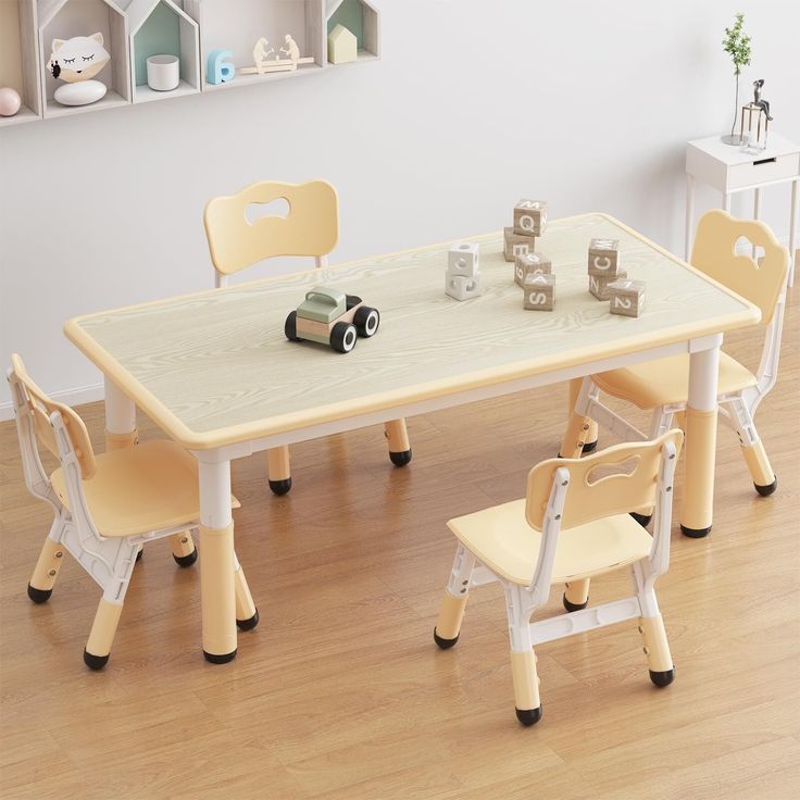 a child's table and chairs set up in a room with white walls, hardwood floors and wooden flooring