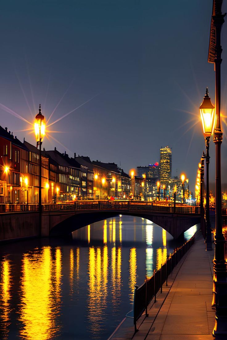 a bridge over a river at night with street lights and buildings in the back ground