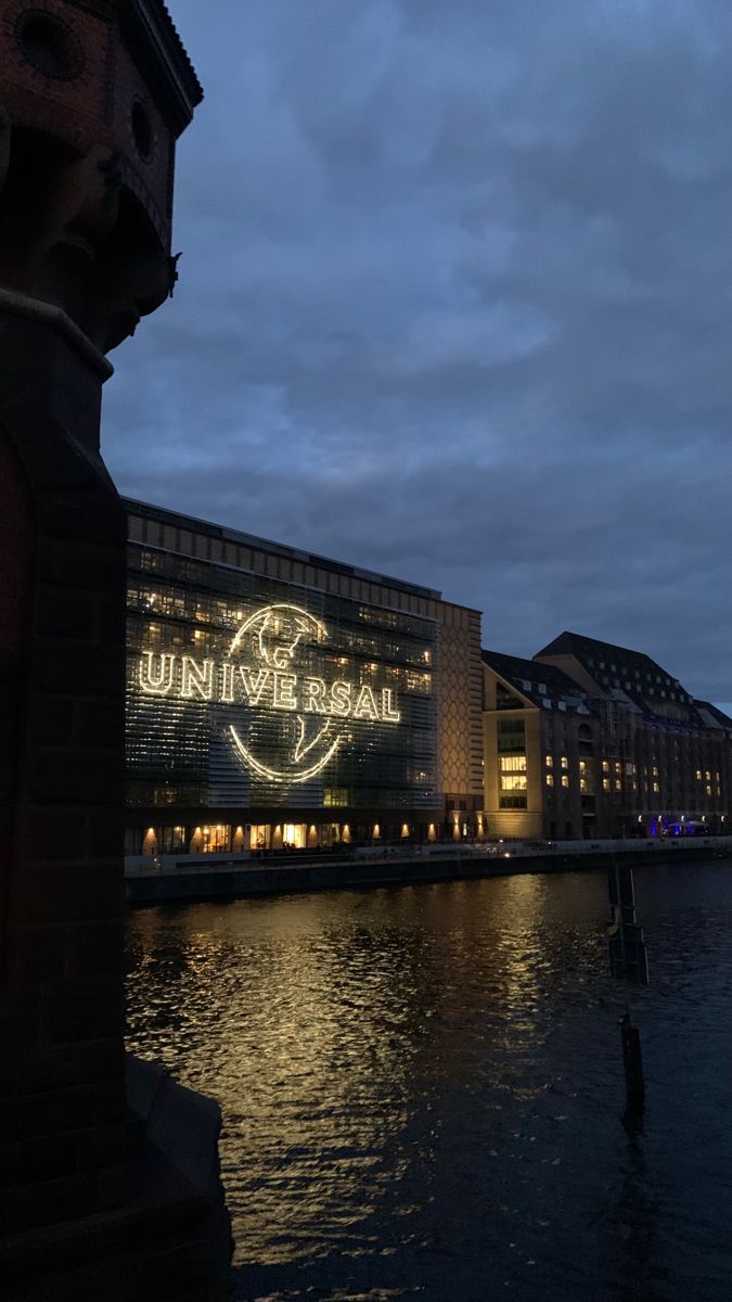 an illuminated sign on the side of a building next to a body of water at night