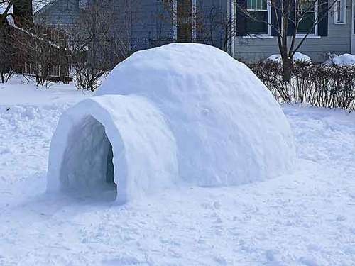 an igloose made out of snow in front of a house