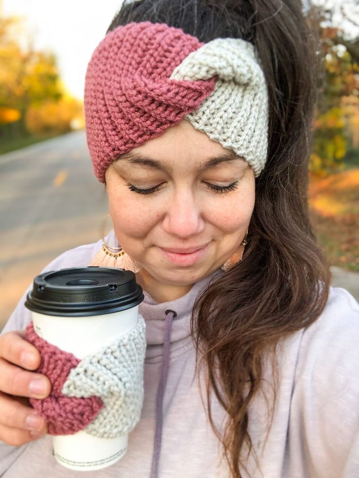 a woman holding a coffee cup and wearing a knitted headband with her hands