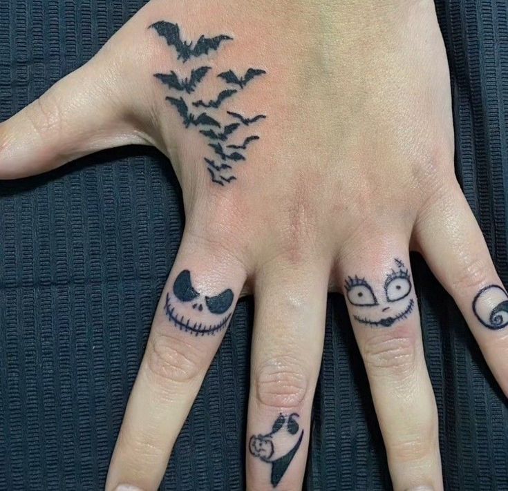 a person's hand with tattoos on it and two fingers that have faces drawn in them