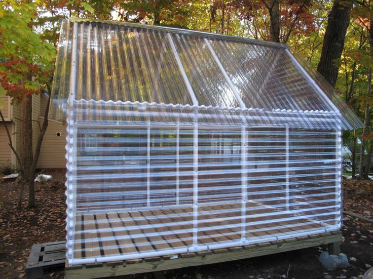 a house made out of plastic sheeting in front of some trees and leaves on the ground