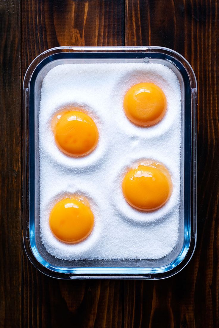 four eggs in a baking dish with sugar on the bottom and yogurt on top