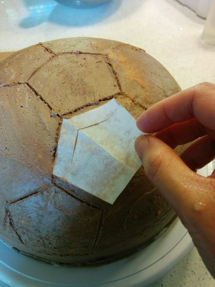 a person is placing a piece of white paper on top of a brown and white soccer ball