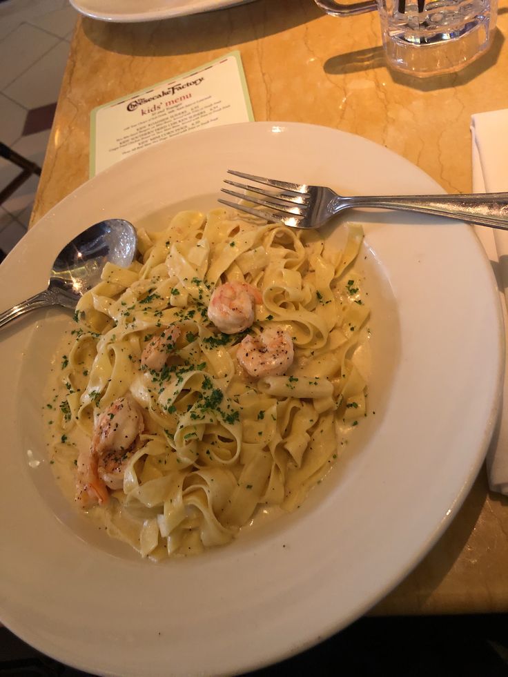 a white plate topped with pasta and shrimp