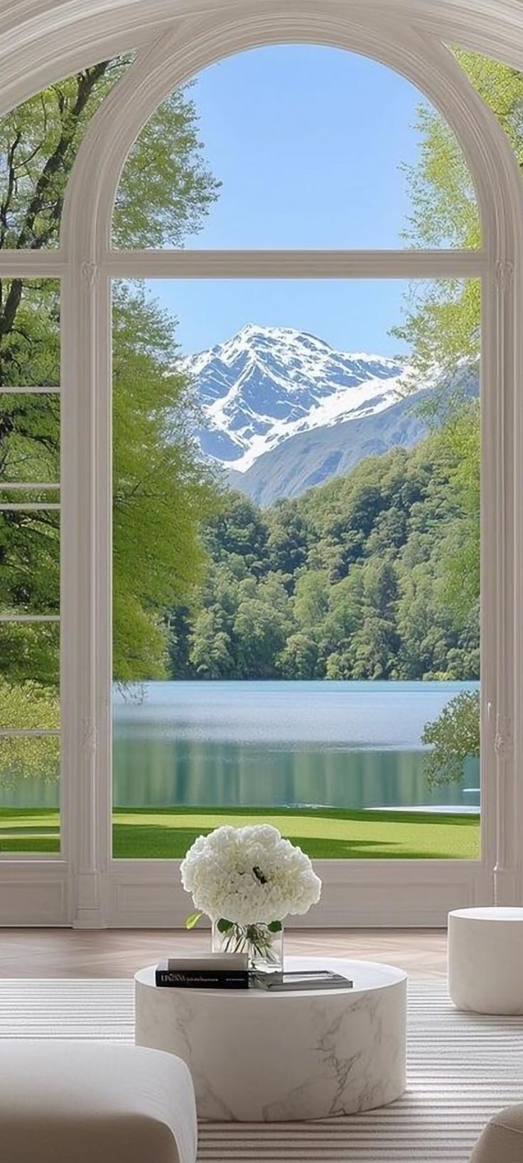 a living room with an open window looking out onto a lake and mountains in the distance