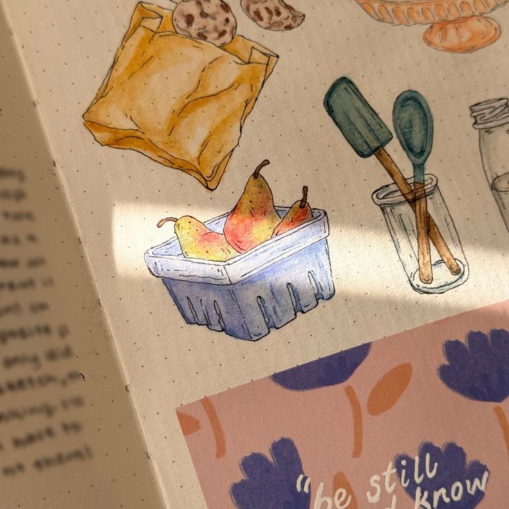 an open book with drawings on it and some food items in the bottom right corner