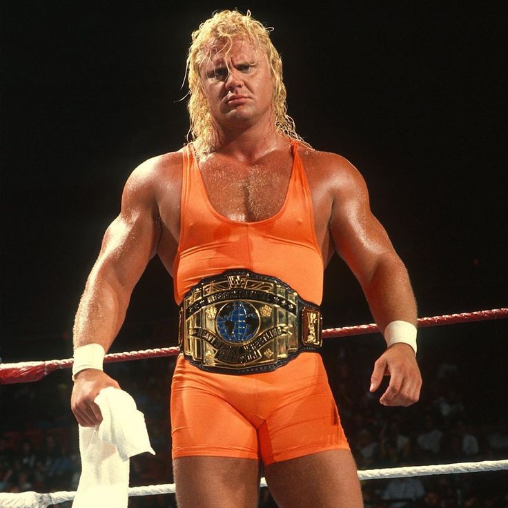 a man in an orange wrestling suit standing next to a rope