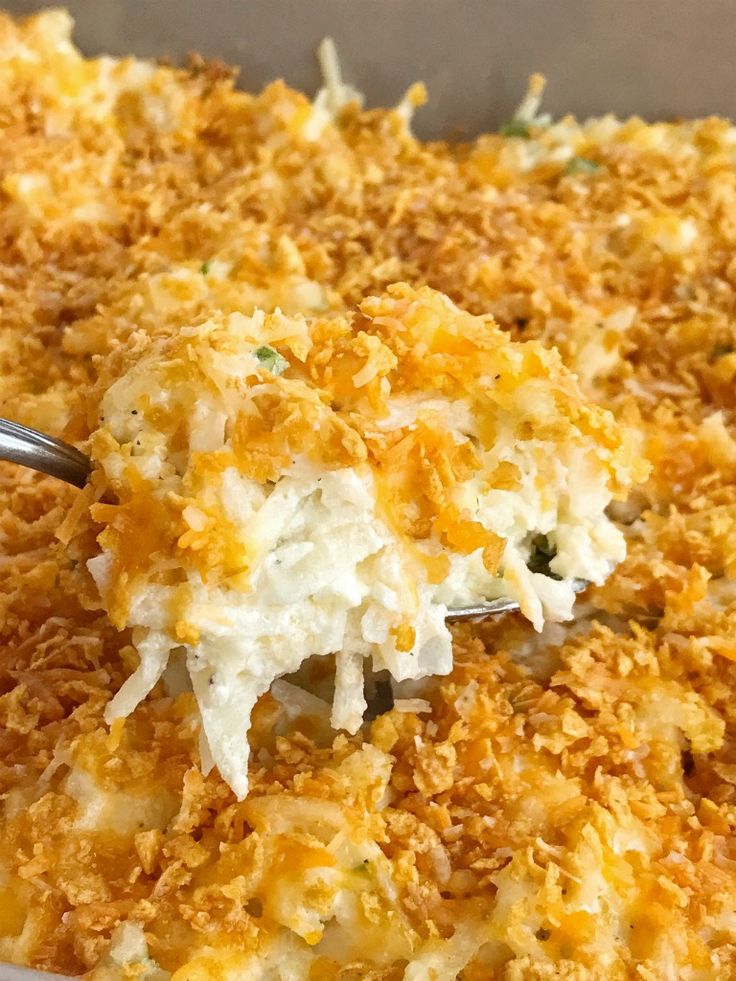 a casserole dish with cheese and other toppings being spooned into it