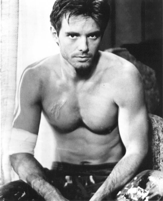 a shirtless man sitting in a chair with his hands on his hips and looking at the camera