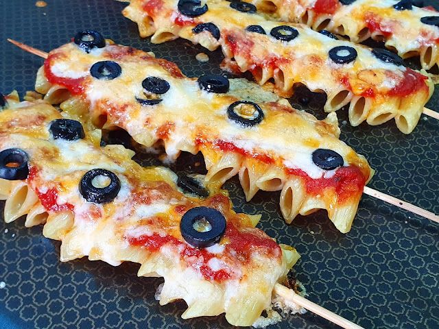 several pieces of pizza with olives and cheese on skewers ready to be eaten