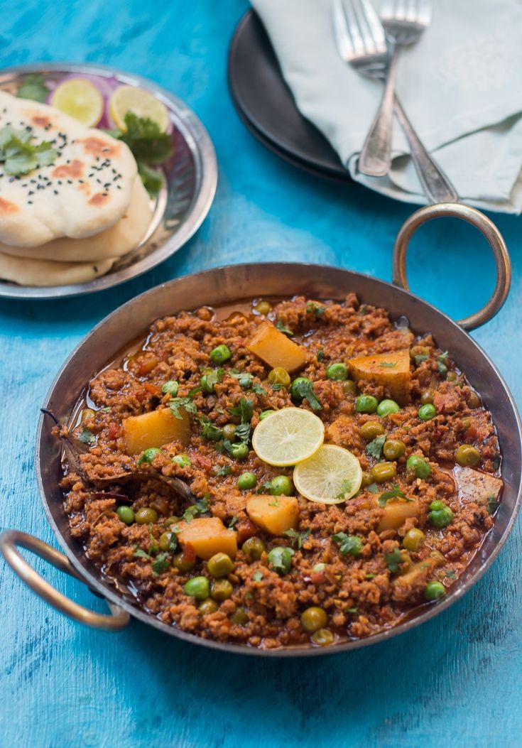 a pan filled with food sitting on top of a blue table covered in silverware