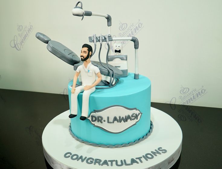 a cake with a man sitting on top of it that is shaped like a dentist's chair