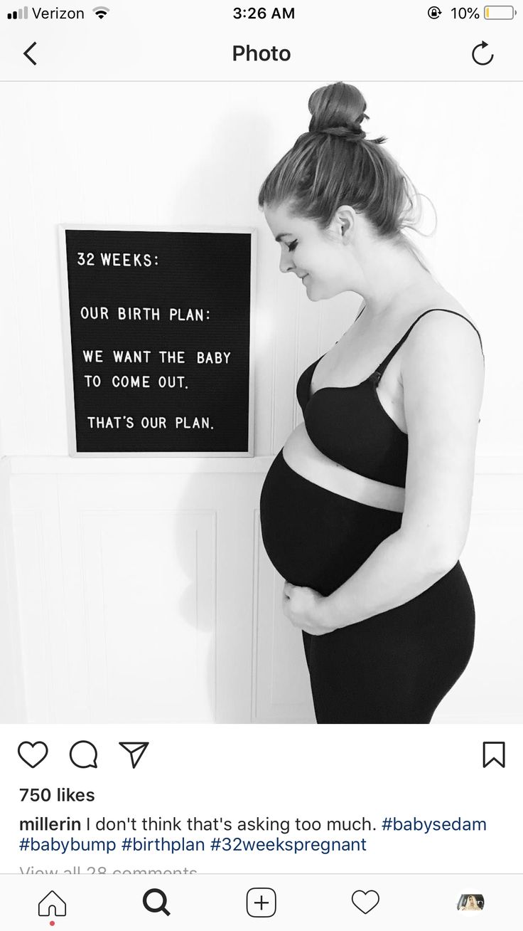 a pregnant woman standing in front of a sign