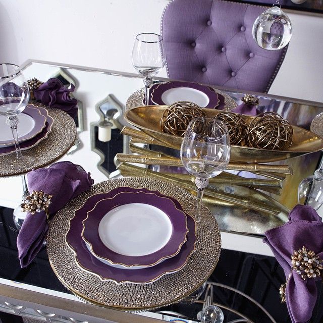 the table is set with purple and gold plates