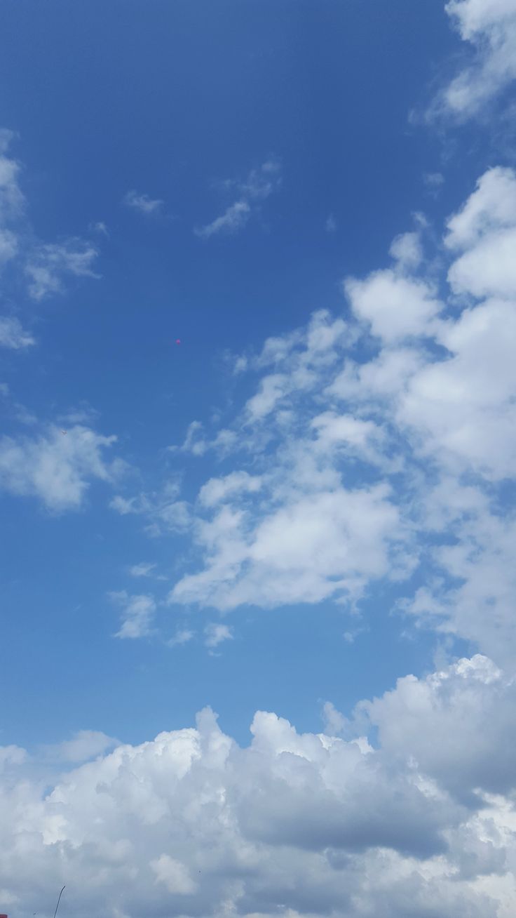 a kite flying high in the sky on a sunny day with clouds and blue sky