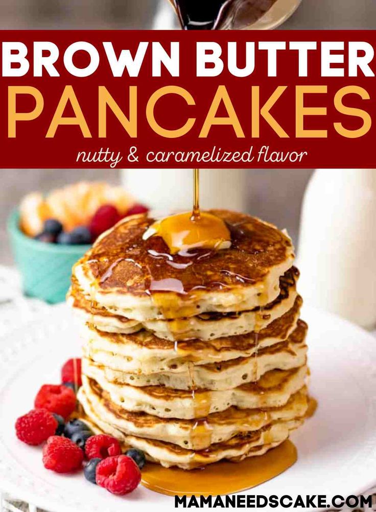 a stack of pancakes with syrup being drizzled on top and berries in the background