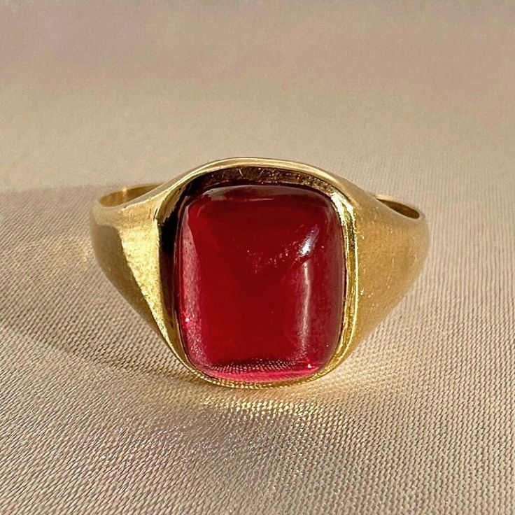 Antique 18k yellow gold ring from the United Kingdom. This signet ring features a vibrant synthetic ruby cabochon. Great antique condition Size: 7.5 resizable* Weight: 3.5 grams Band: 11.1 mm (front), 1.7 mm (back) Synth Ruby: 8.3 mm x 10.0 mm Hallmarks:18CT Modern Gold Signet Ring With Cabochon, Formal Gold Cabochon Signet Ring, Heirloom Red Signet Ring With Polished Finish, Classic Red Ruby Ring, Oval Cabochon, Classic Red Ruby Ring With Oval Cabochon, Gold Ruby Ring Oval Cabochon With Polished Finish, Formal Red Domed Rings, Modern Yellow Gold Signet Ring With Cabochon, Classic Red Signet Ring For Formal Occasions