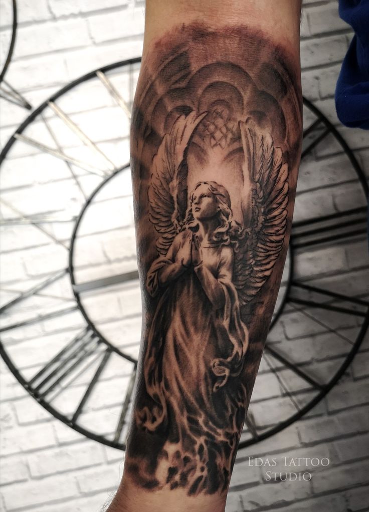 a man with a tattoo on his arm that has an angel holding a baby in it